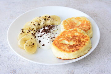 Golden Syrniki with Sliced Banana, Cream and Chocolate Shavings