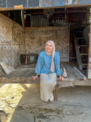 A woman enjoys her time sitting on the porch of a rustic wooden house, smiling under the sun