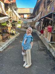 A young woman smiles in a narrow street surrounded by wooden houses in a traditional village
