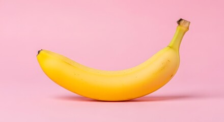 A single ripe yellow banana on a vibrant pink background