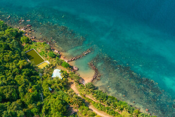 Naklejka premium Aerial view of hidden tropical sandy beach on Phu Quoc Island, Vietnam, surrounded by lush green rainforest, palm trees and clear turquoise sea water. Sustainable tourism and travel in Asia