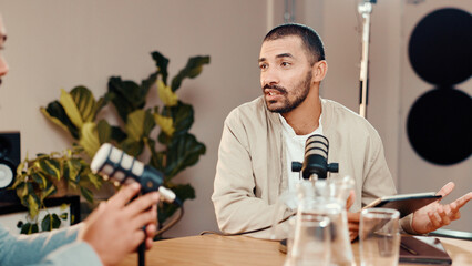 Podcast, mic and man with guest in studio for interview, conversation and broadcast for radio show. Content creation, hosting and presenter with person on tablet for recording, live stream or talking