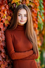 A young woman in a brown sweater leaning against a wall of leaves