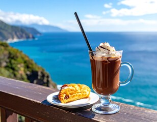 Glass of hot chocolate and pastry on deck overlooking the sea