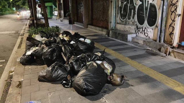 Piles of garbage bags on a sidewalk infested with rats highlighting urban sanitation issues