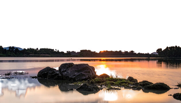 Sunset on lake, rocks, water reflecting light, dark sky above