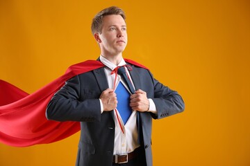 Businessman wearing superhero costume on yellow background