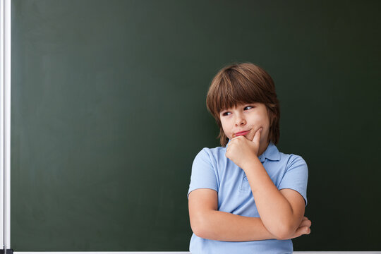 Back to school. Boy near green chalkboard indoors, space for text