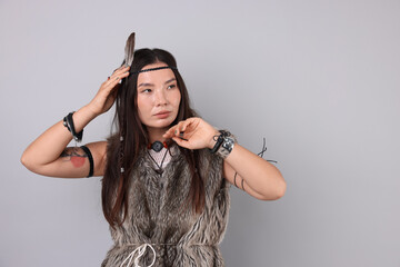Shaman woman in feather headdress on light grey background, space for text