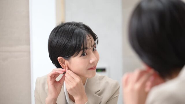 鏡の前で笑顔で身だしなみを整える女性の美容シーン　アクセサリーを付ける