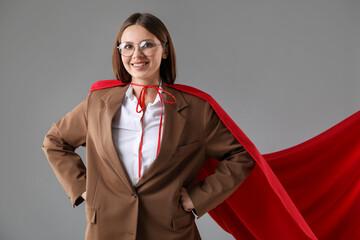 Businesswoman wearing superhero cape on grey background © New Africa