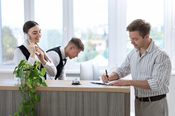 Receptionist working with guest at reception desk in hotel