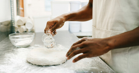 Baker, hands and pouring water on dough for bread, cooking food and restaurant cuisine. Person, liquid and ingredients in kitchen for hospitality catering, meal prep and gluten free sourdough recipe.