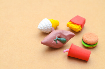 A visual metaphor showing how processed foods like burgers and soda can lead to serious liver conditions like fatty liver disease.