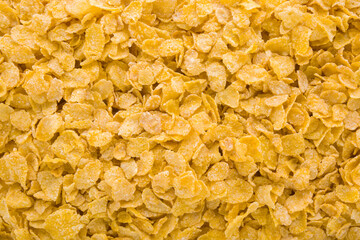 Yellow dry corn flakes background. Closeup. Top down view.