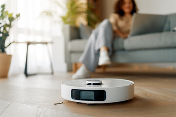 Plakat White robotic vacuum cleaner on wooden floor