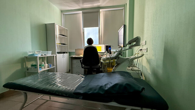 In a dimly lit clinic, an Asian woman ponders screens, reminiscent of Odd Day or Digital Detox celebrations - Powered by Adobe