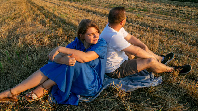 Sunset whispering secrets to a pensive Caucasian couple on straw-strewn fields, echoing Lammas harvest and golden silence