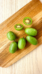 Mini kiwi berries basking on rustic board, vibrant antioxidant gems, exploring exotic flavors, Kiwi Fruit Festival delight