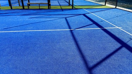Shadows dance on electric blue paddle court, evoking competitive energy, Dia de Muertos mystery,...