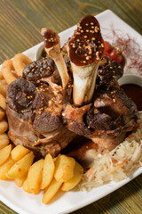 Beef shank on the bone with fermented cabbage, pickled tomatoes, baked potatoes, and teriyaki sauce