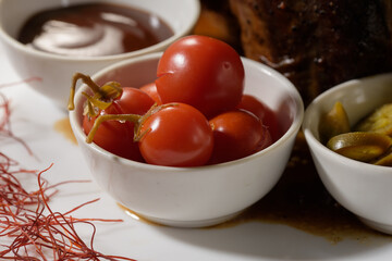 plates with marinated tomatoes, pickled green hot peppers and teriyaki sauce for a meat dish
