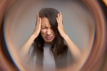 Woman closing eyes in pain suffering from migraine aura and sensory overload