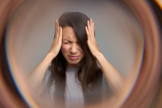Woman closing eyes in pain suffering from migraine aura and sensory overload