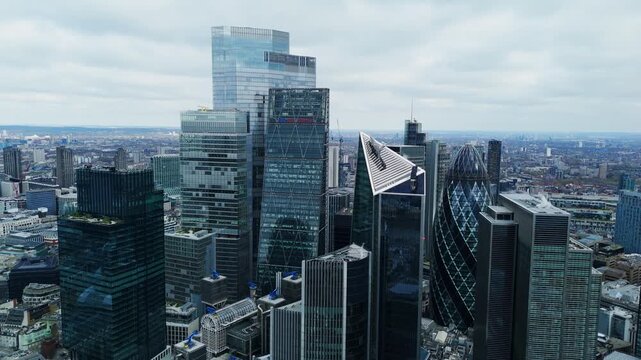 Aerial view of towering skyscrapers pierce the overcast sky, their glass facades reflecting the diffused light across the City of London, London, United Kingdom.