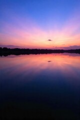 Fototapeta premium A still, calm body of water reflecting a serene sunrise or sunset, symbolizing peace, renewal, and spiritual reflection. A perfectly still, glassy body of water that mirrors a vibrant yet soft