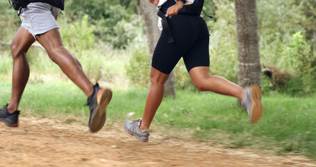 Fototapeta premium Fitness, legs and couple running in forest for health, wellness or training outdoor. Man, woman and shoes of trail runner in woods for cardio workout, endurance exercise and practice in nature