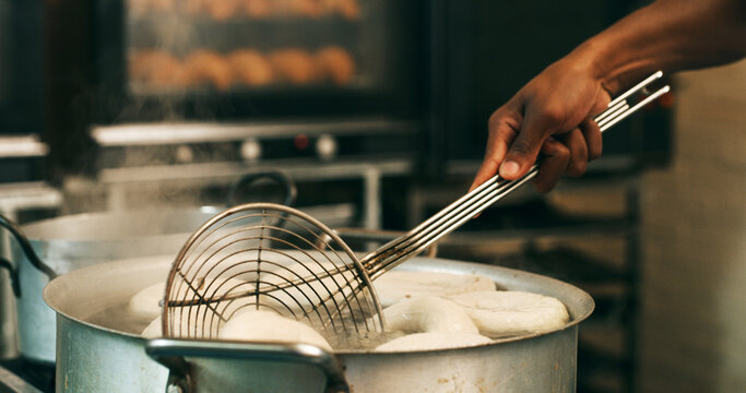 Hands, baker or tool for frying donuts in kitchen for breakfast order, baking process or gastronomy. Catering, person or strainer in bakery for small business, snack production or dessert preparation