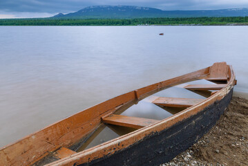 Beautiful evening view of a mountain lake with boats on calm water, surrounded by hills and soft sunset light.