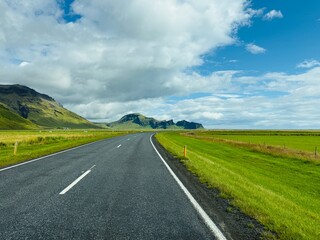 Empty road surrounded by green meadows im the south of Iceland 