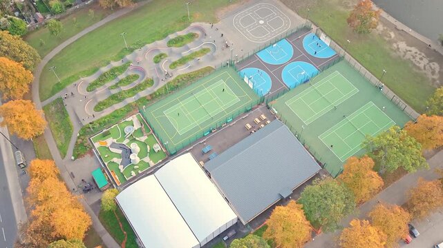 Top-down aerial reveals Hillsborough Park&rsquo;s full suite of sports facilities, three green tennis courts, basketball courts, grey multi-use court, playground, and winding BMX pump track in Sheffield.