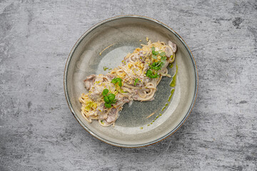 Spaghetti pasta with creamy mushroom sauce, parmesan cheese and fresh herbs served on a gray ceramic plate with rustic background