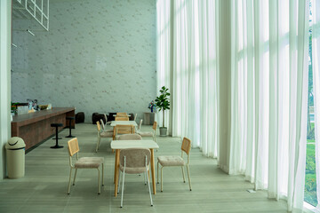 Minimalist cafe interior with wooden furniture, soft natural light, and tall sheer curtains. Ideal for modern coffee shop concepts, cozy dining spaces, and Scandinavian interior design themes.