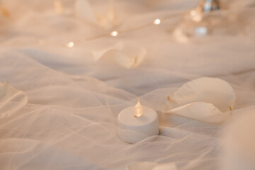 Romantic Soft Focus Candlelight Scene with White Petals and Tulle. Warm Lighting, Wedding Decor, Intimate Mood, Beige and Cream Tones.