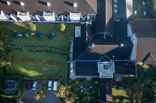 Aerial view of the grand St. Andrew's Hotel nestles amidst manicured green lawns, with its dark roofs contrasting against the bright grass, Nuwara Eliya, Central Province, Sri Lanka.