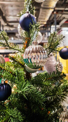 A decorated Christmas tree with various ornaments. The tree features green branches adorned with blue and silver baubles, creating a festive atmosphere.