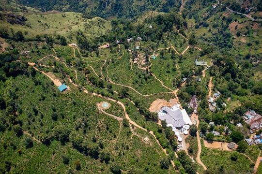 Aerial view of winding pathways snaking through verdant hillsides, revealing scattered buildings and lush landscapes in a tapestry of green and brown, Ella, Uva Province, Sri Lanka.