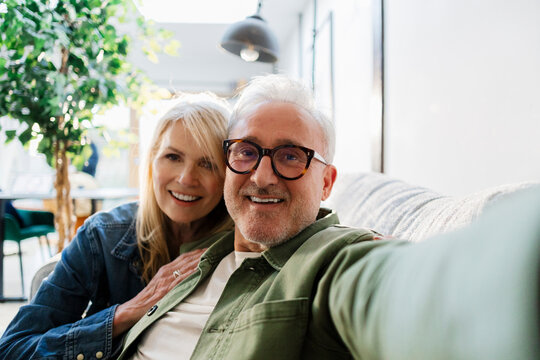 Senior couple taking a selfie at home, smiling and enjoying their retirement lifestyle - Powered by Adobe