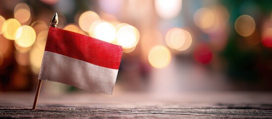 Small Indonesian flag displayed on a wooden surface with blurred festive lights in the background