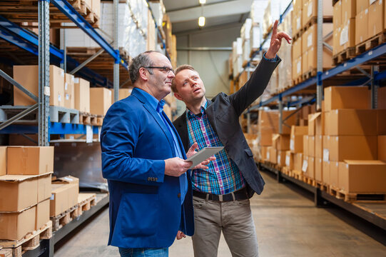 Employees in warehouse discussing logistics with tablet