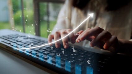 A close-up of hands typing on a keyboard with a financial graph overlay, symbolizing data analysis and business growth in a modern office setting. Copula
