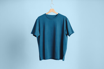 Crewneck model T-shirt in high-quality teal blue cotton, hanging on a wooden hanger. Neutral, clean, and professional background. Ideal for customizable e-commerce display.