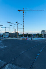Urban construction site with many cranes under blue sky