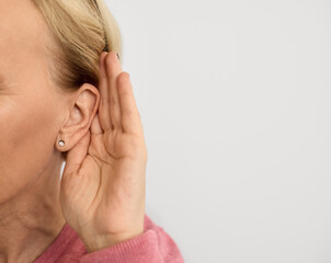 Mature woman listening sound with hand near ear for hearing check-up. Hearing test concept