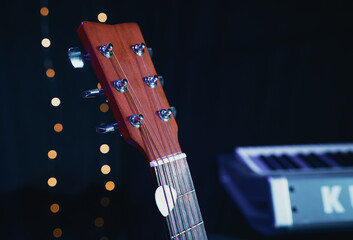 Beautiful acoustic guitar resting on a stand on a darkened stage floor, illuminated by a warm spotlight. Perfect for folk, country, live music, and intimate performance concepts.