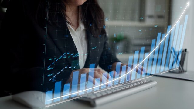 A focused businesswoman in a black suit analyzes data insights using a computer with financial graphs. The scene captures a modern office environment dedicated to success. Copula